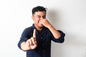 Adult Asian man covering nose with smelly expression by showing 1 finger