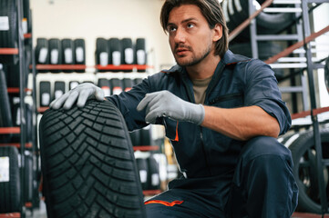 Warehouse with many tires. Man is in the tire fitting car service