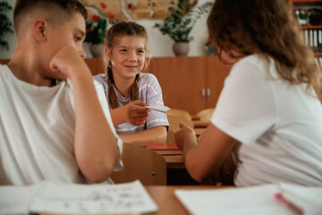 Fototapeta premium Taking the cheat sheet. Pupils, kids in the classroom together
