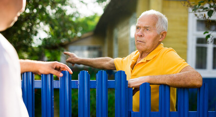 Good neighbors talk on border of their farms