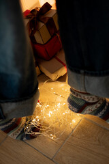 Feet in warm socks sneaking near stacked Christmas gifts.Feet in fluffy socks creeping by stacked...
