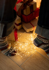 Feet in cozy winter socks tiptoeing by a mountain of Christmas gifts