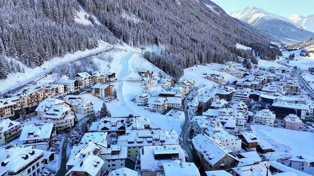 Ischgl, Austria, Europe: Aerial view of ski resort in snowy Tyrolean Alps. Charming village landscape with chalets and hotels surrounded by snow-capped peaks, sunny day, clear blue sky
