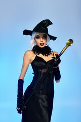 Dressed in a stunning witch costume, a young woman confidently poses with a stylish wand.