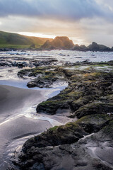 Sun setting behind rock formations, seascape at Ballintoy on the Causeway Coast of Northern Ireland.