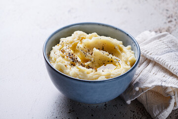 Mashed potatoes with butter and pepper in blue bowl.