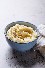 Mashed potatoes with butter and pepper in blue bowl.