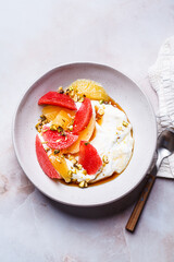 Greek yogurt with nuts and citrus slices.