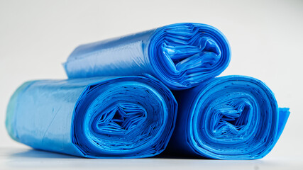 Three rolls of blue plastic garbage bags on white background. Household cleaning products. Photo....