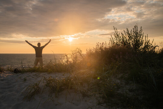 silhouette of a happy man in the sunset in the dunes near the ocean