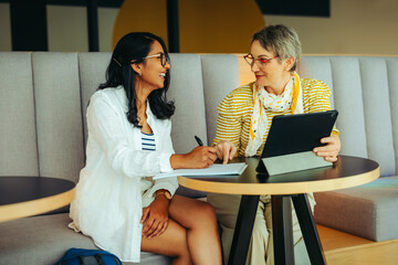 Fototapeta premium Happy student and teacher sharing a positive learning moment in a relaxed environment with digital tablet and notebook