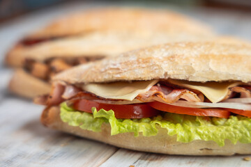 Cheese and bacon baguette close up, more baguettes on the background
