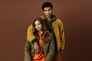 Fototapeta premium A fashionable couple showcases their stylish autumn attire against a rich, earthy background.