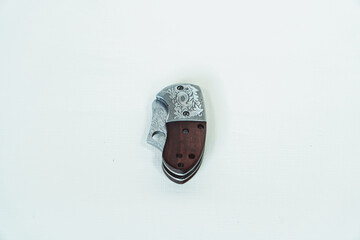 Mini folding knife with patterns on some parts of the blade isolated on a white background....