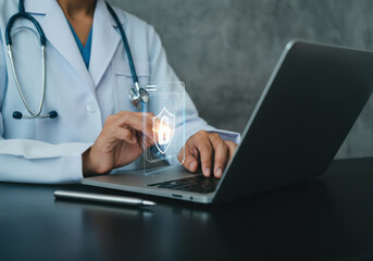 Medical professional working on a laptop while ensuring patient data security in a healthcare setting