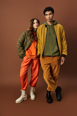 A stylish couple stands confidently in colorful autumn outfits, radiating fashion and warmth.