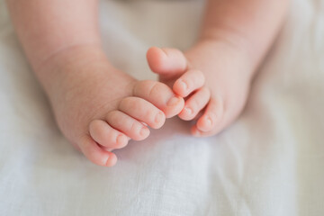 Tiny newborn infant baby feet and toes on white background. Soft newborn baby foot legs under the white blanket. Close up of infant barefeet. Maternity tenderness parenthood birthday. Happy Family