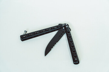 Partially open matte black balisong or butterfly knife isolated on white background. Close-up of a sharp balisong knife or butterfly knife in various positions on a white background