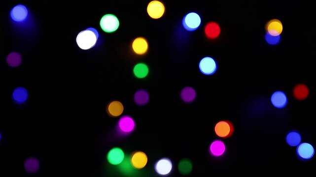 Una toma de cerca de varias luces de colores en forma de c&iacute;rculos en movimiento en la oscuridad. Desenfoque