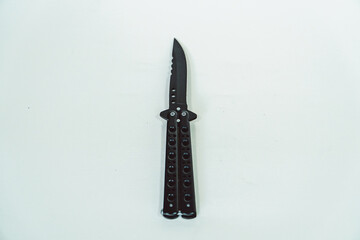 Partially open matte black balisong or butterfly knife isolated on white background. Close-up of a sharp balisong knife or butterfly knife in various positions on a white background