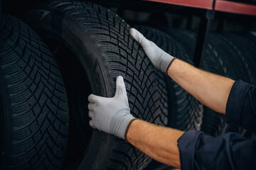 Close up view, taking the tire. Man worker is maintenance station with wheels