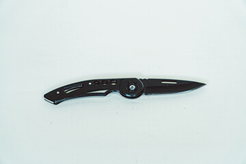 Obraz premium Mini size folding knife of solid black color partially opened isolated on white background. Close-up view of a black folding knife used for various outdoor or survival activities
