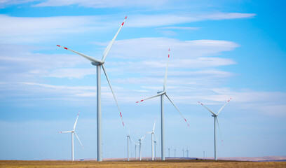 Fleet of power generators in motion. The blades of the wind farm rotate against the sky. The...