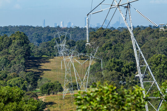 High voltage electricity power lines and power poles with Brisbane City CBD in background.