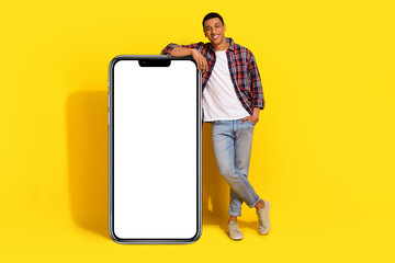 Full length photo of attractive guy wear checkered shirt lay hand on ui on smartphone display...