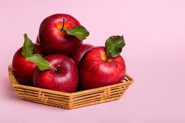 Ripe garden apple fruits with leaves in basket on wooden table. Top view flat lay with copy space