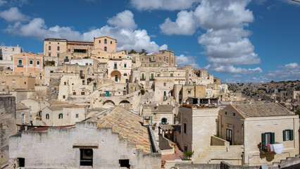 Explore the ancient stone houses of Matera, Puglia under a vibrant blue sky in Italy