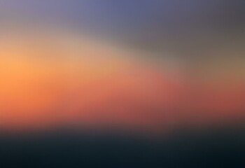 Obraz premium Blurred gradient background of a sunrise, sunset, or twilight sky with warm orange, pink, and purple tones fading to a dark blue or black horizon.