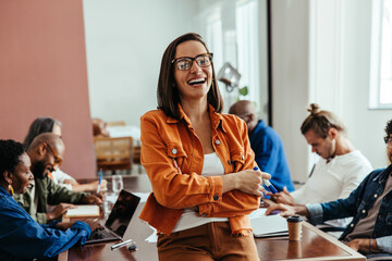 Stylish businesswoman in colorful boardroom engaged in creative teamwork