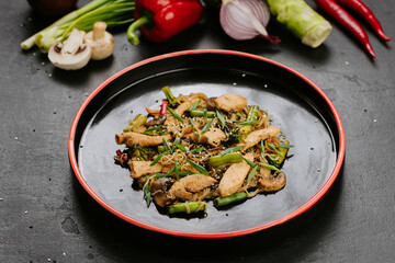 Stir-fried chicken with vegetables and glass noodles, garnished with sesame seeds for a healthy meal