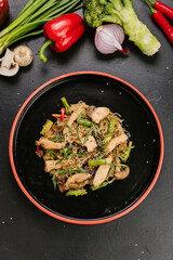 Stir-fried chicken with vegetables and glass noodles, garnished with sesame seeds for a healthy meal