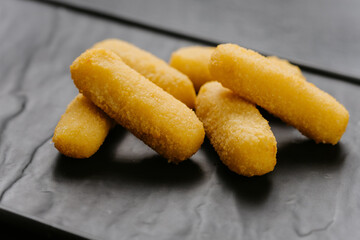 Crispy cheese sticks served on a black plate, perfect snack or appetizer for any occasion