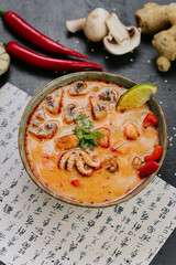 Spicy Tom Yum soup with seafood, mushrooms, and chili served with lime and herbs in Asian style