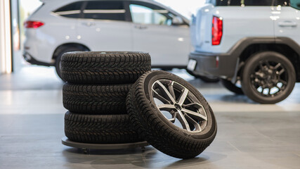 New wheels with studded tires against the background of new cars. 