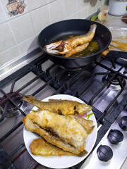 fried fish lies on a plate and in a frying pan