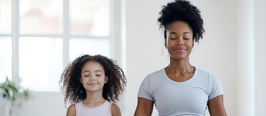 Obraz premium Mother and daughter practicing yoga together in a bright, peaceful room.