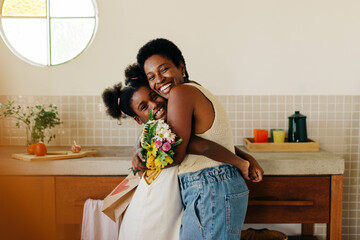 Mother and daughter embrace in floral surprise at home