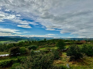 Expansive View of Rolling Hills and Verdant Valleys in Auvergne-Rhône-Alpes from Aire de Lafayette Lorlanges, Highlighting Lush Vegetation and Dramatic Cloudscapes Along the A75 Motorway