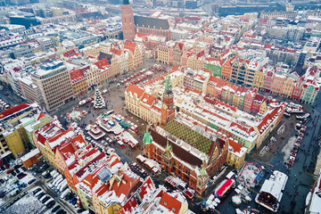 Aerial view of European town covered in snow with red-roofed buildings in winter season. Christmas market and decorated streets Wroclaw city, Poland