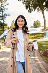 A beautiful young woman walks through a colorful autumn park, smiling while enjoying her coffee.