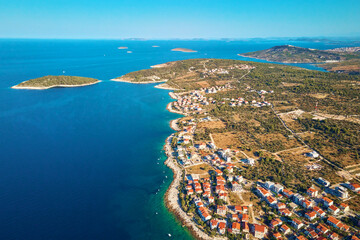 Fototapeta premium Aerial view of Adriatic sea coastline with coastal village and boats along shoreline. Panorama of tourist town Rogoznica in Croatia on Adriatic Sea. Summer travel concept