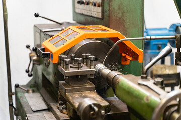 A close up of a lathe machine with an orange safety guard, machine is cutting a piece of metal. © bulentbaris