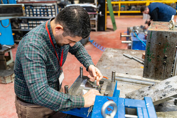 Lathe worker man working with a vernier and milling machine in a factory, using a caliper to check measurement.