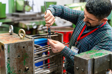 Lathe worker man working with a vernier and milling machine in a factory, using a caliper to check measurement.