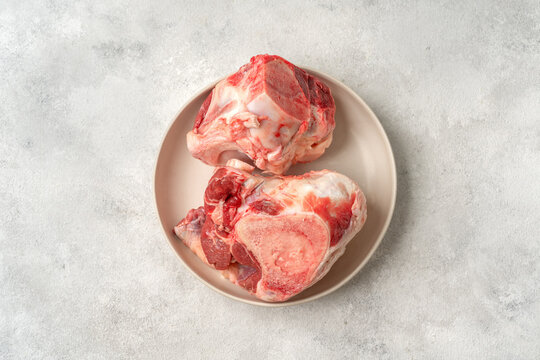 Raw beef bones for making broth in a white plate on a culinary kitchen table top view with a copyspace