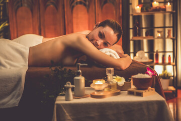 Aromatherapy massage ambiance or spa salon composition setup with focus decor candles and spa accessories on blurred woman enjoying blissful aroma spa massage in resort or hotel background. Quiescent